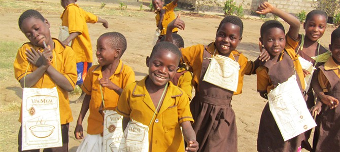 Children in Malawi with repurposed Vitameal bags used to carry school supplies
